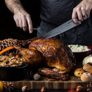 Thanksgiving dinner displayed with turkey being carved by chef