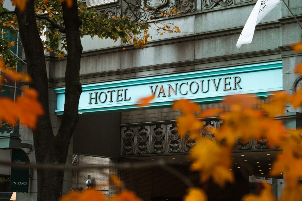 The entrance to Hotel Vancouver's driveway with orange November autumn leaves on a tree.