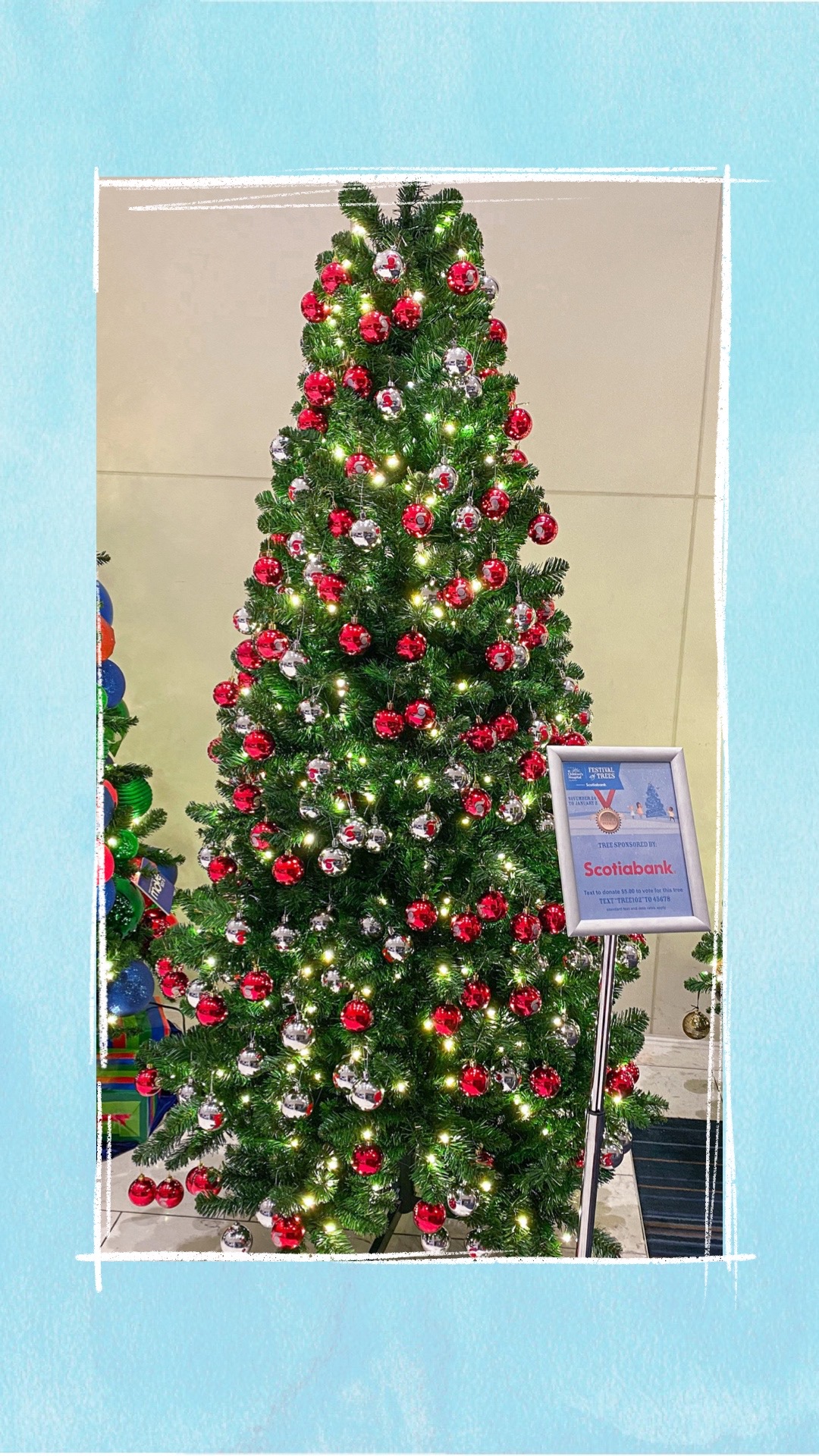 A holiday tree decorated with red and silver ornaments for the BCCHF Festival of Trees